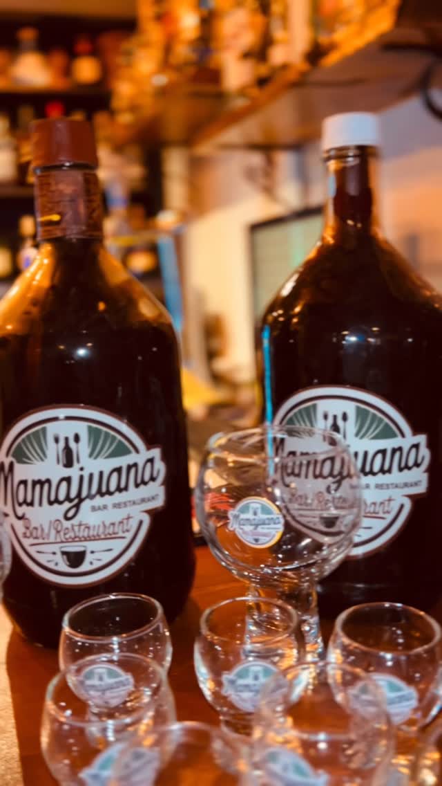 Botellas y vasos de mamajuana con el logotipo de la casa