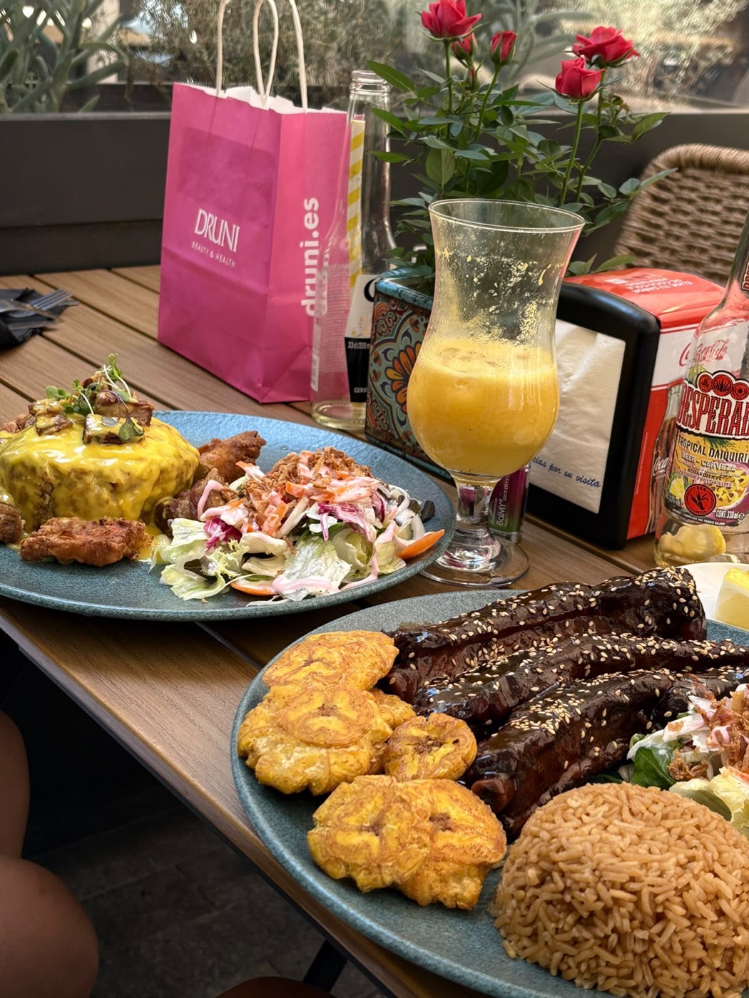 Mesa en la terraza con costillas, tostones, arroz y un zumo